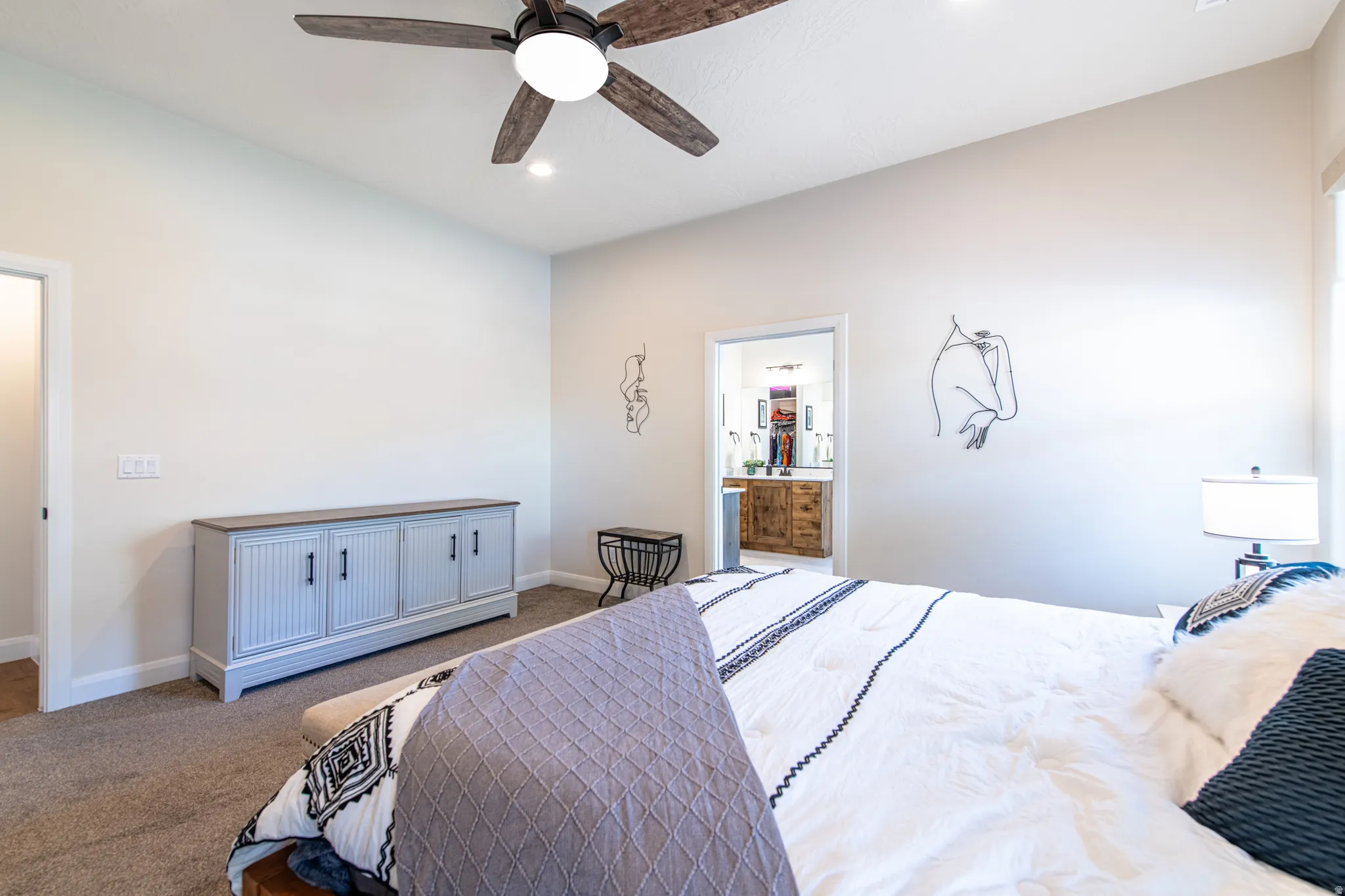 Carpeted flooring, vaulted ceiling, recessed lighting, ceiling fan with integrated lighting, and a doorway opening to a dual vanity bathroom