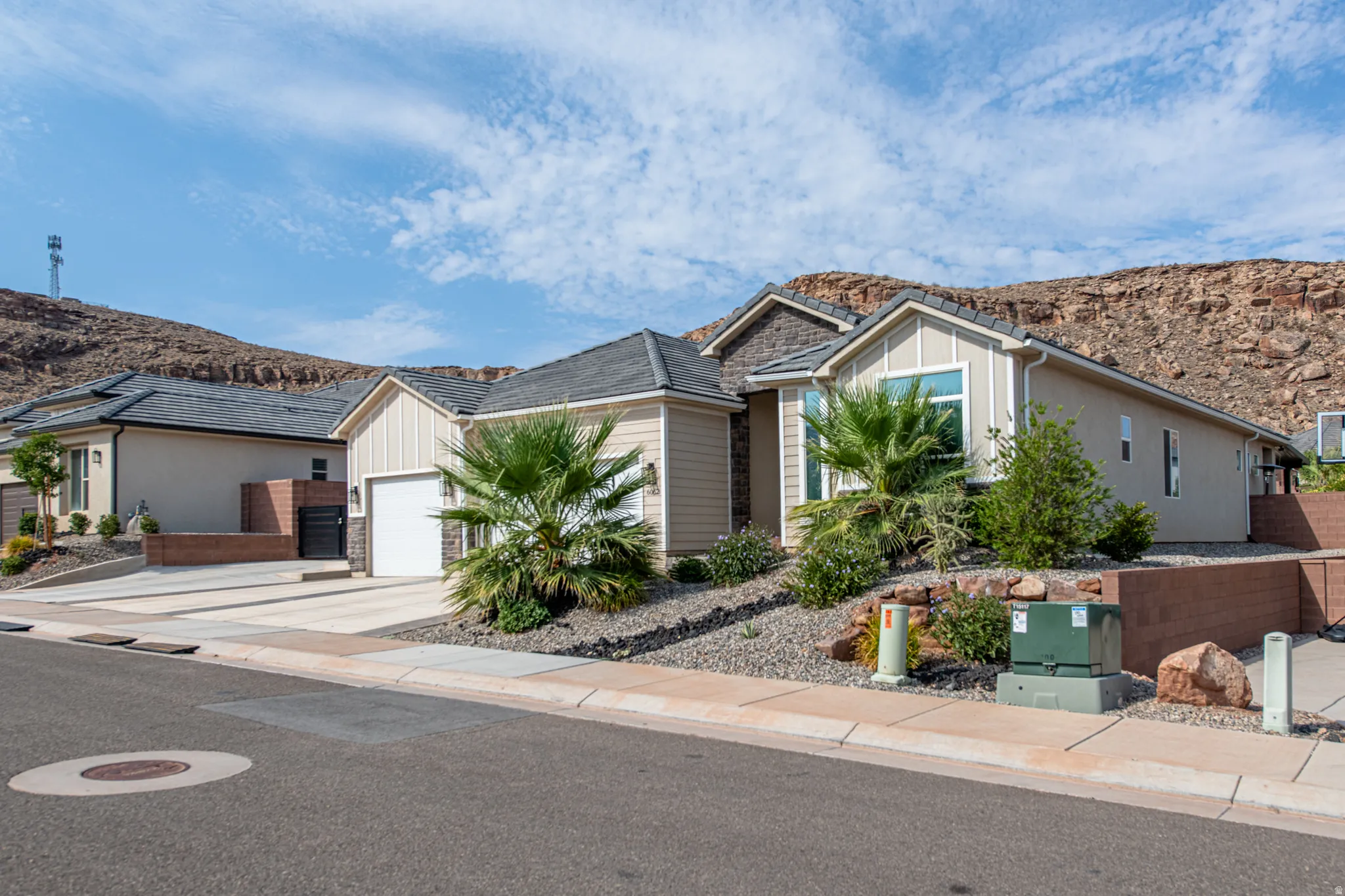 Contemporary exterior with a prominent single-car garage, pitched shingle roof, and a meticulously landscaped front yard featuring rock and shrubbery