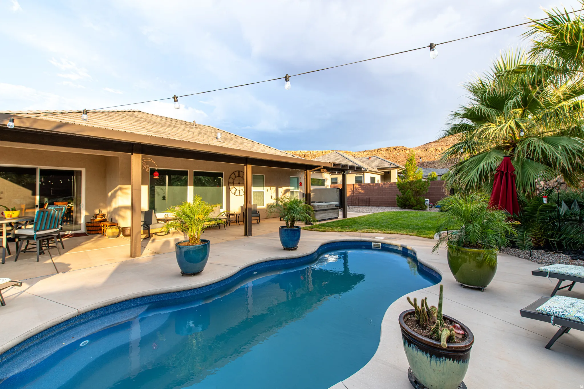 Curved swimming pool with surrounding concrete patio and covered patio area