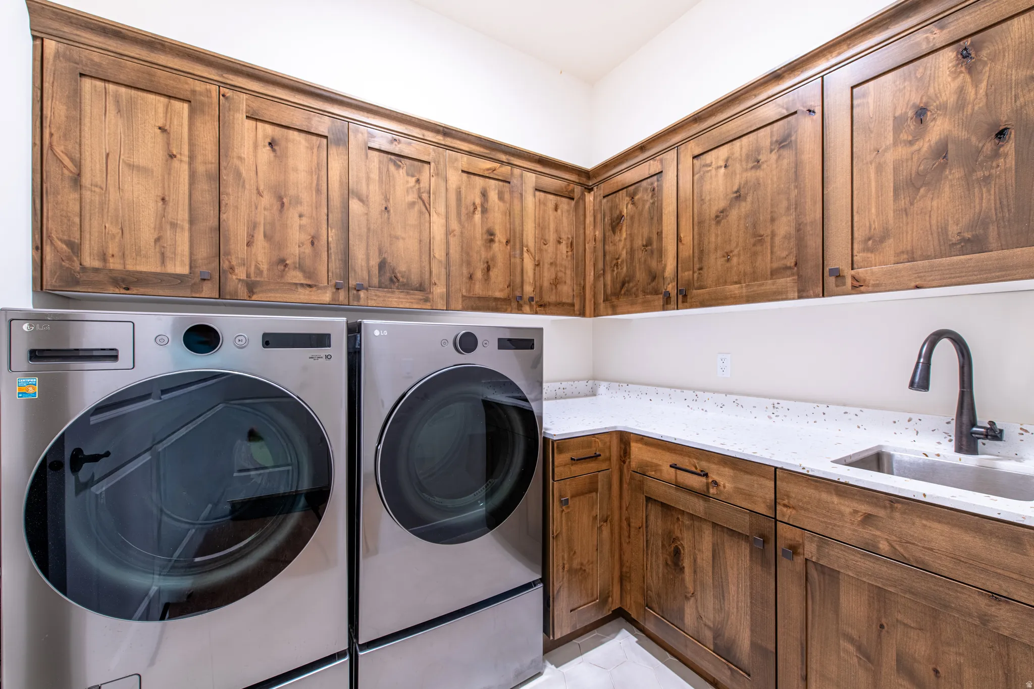 Built-in wood cabinetry with crown molding, light-toned countertop, and stainless steel sink with a dark-finish faucet