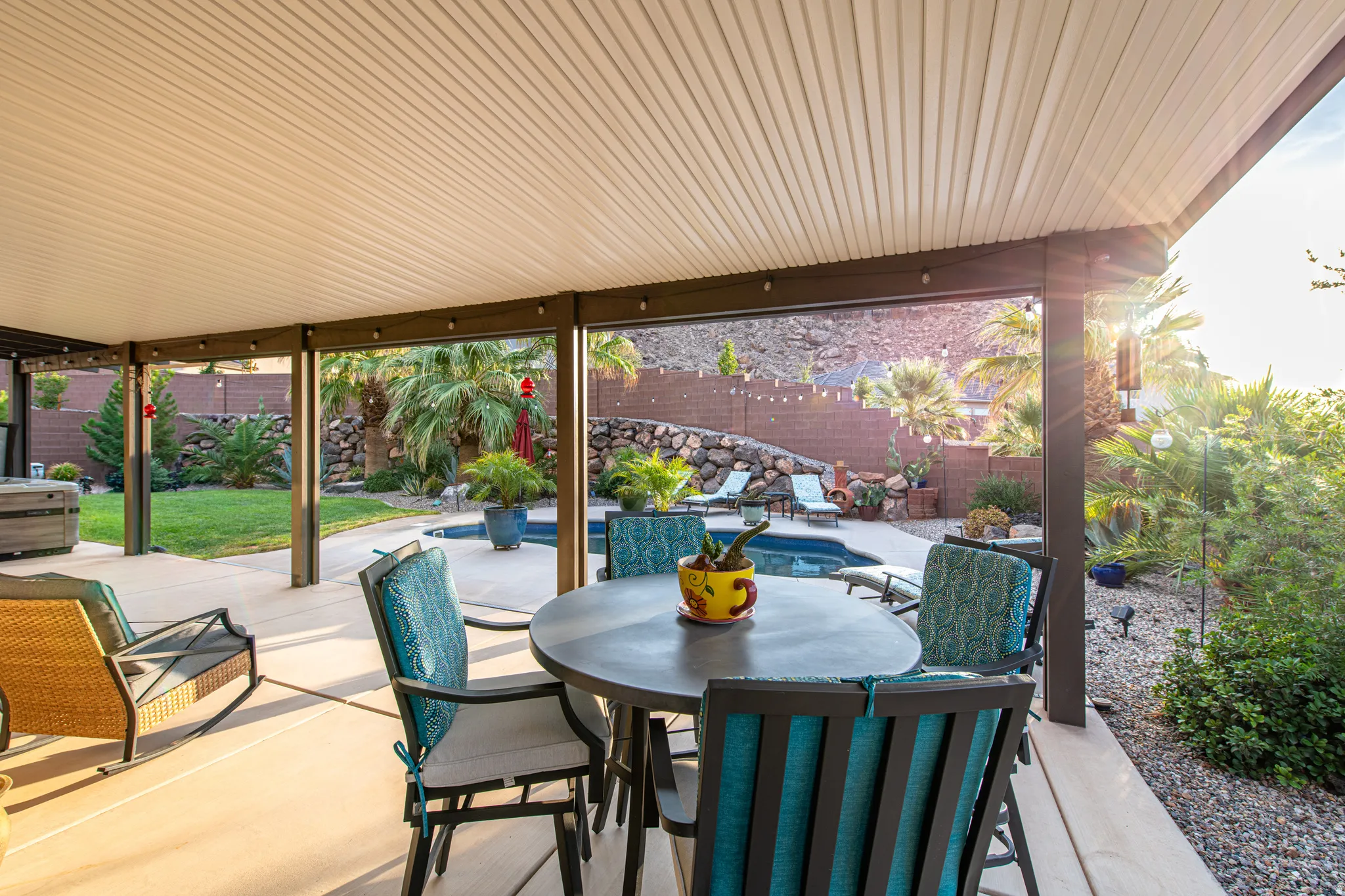 Expansive covered patio with concrete flooring, overlooking a swimming pool, lawn area, and mature landscaping