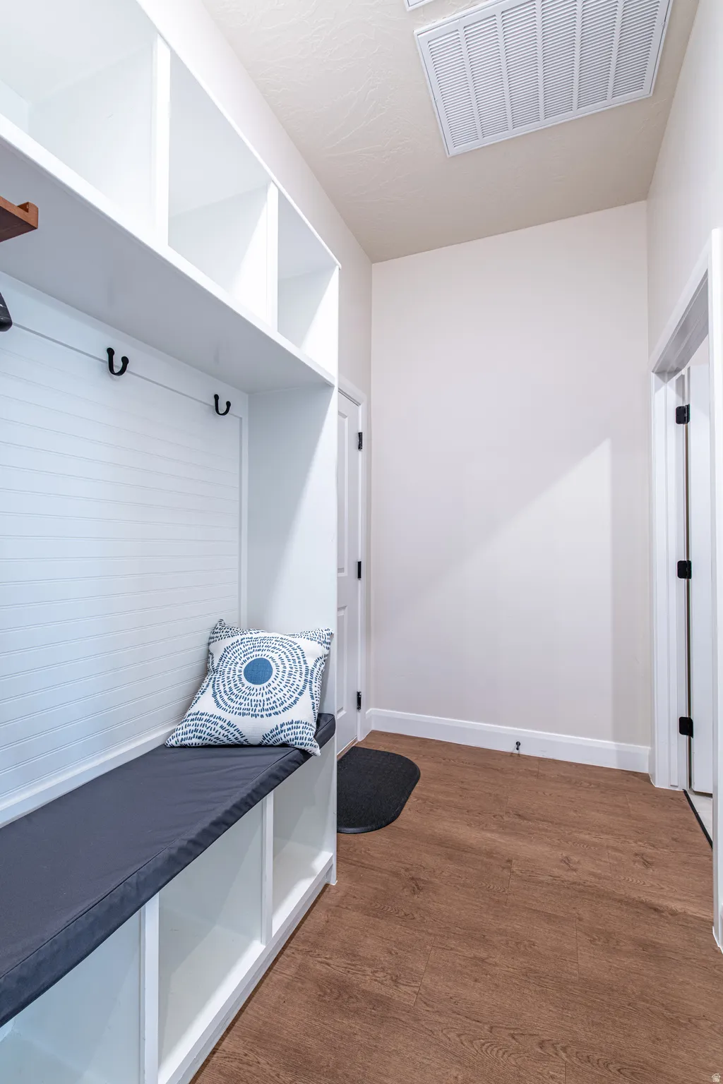 Built-in storage bench with hooks, open shelving, and wood-finish flooring