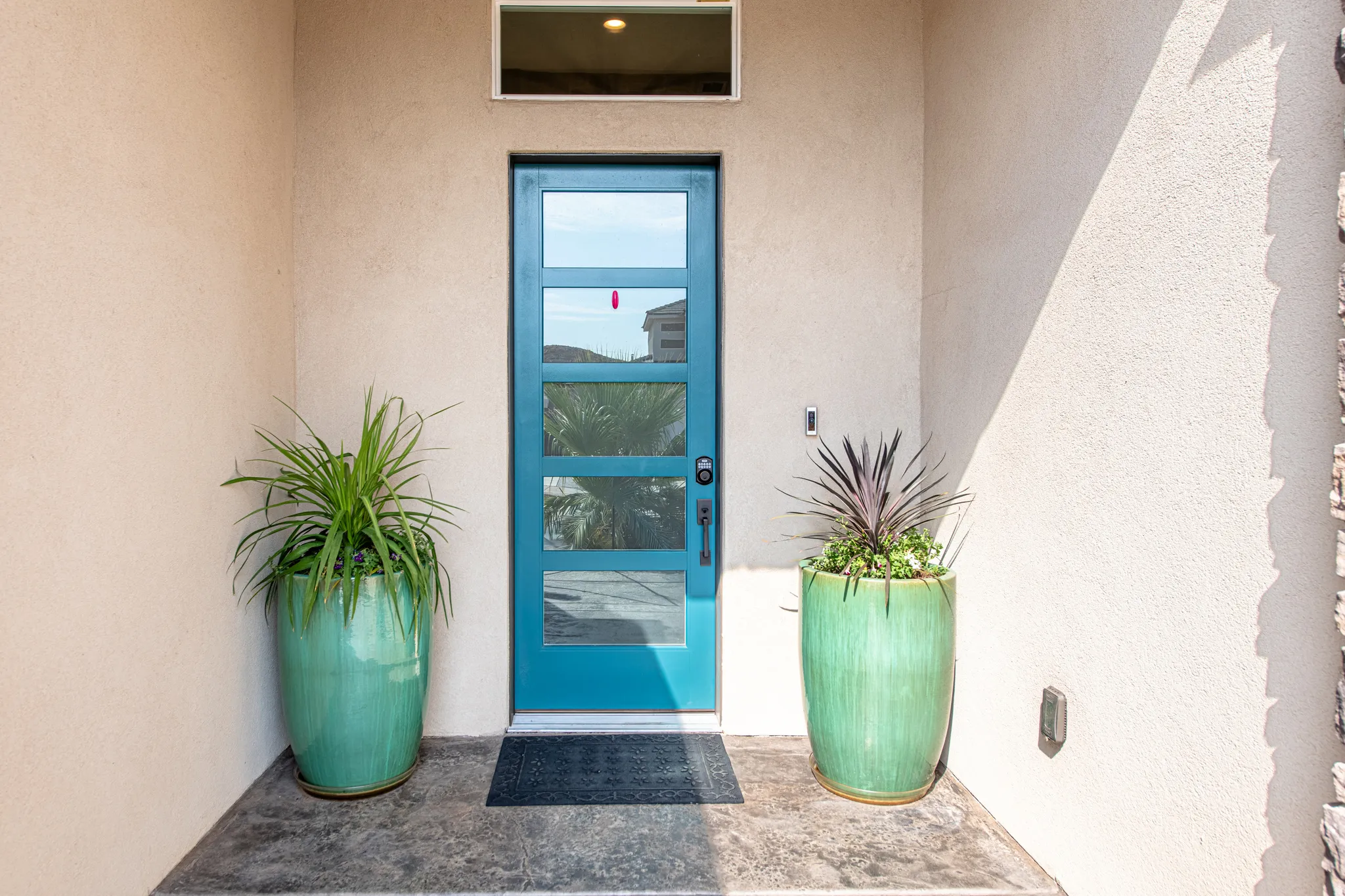 Contemporary entry door with multiple glass lites, transom window, and stucco exterior
