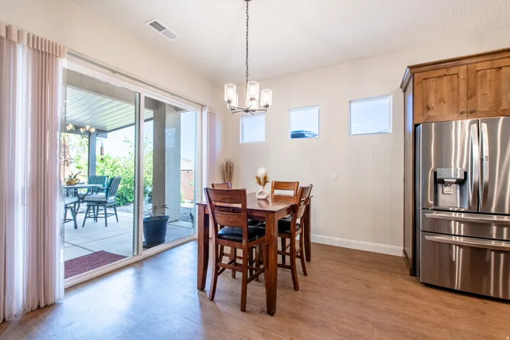 Wood-finish flooring, sliding glass patio doors, three transom windows, a chandelier light fixture, and wood cabinetry