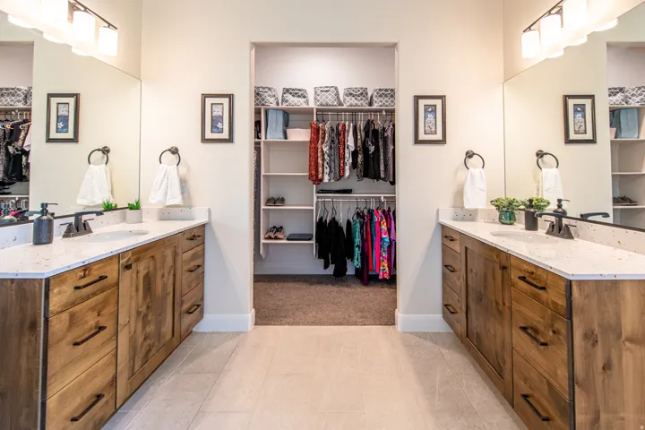 Dual vanities with wood-finish cabinetry, integrated sinks, and individual mirrors