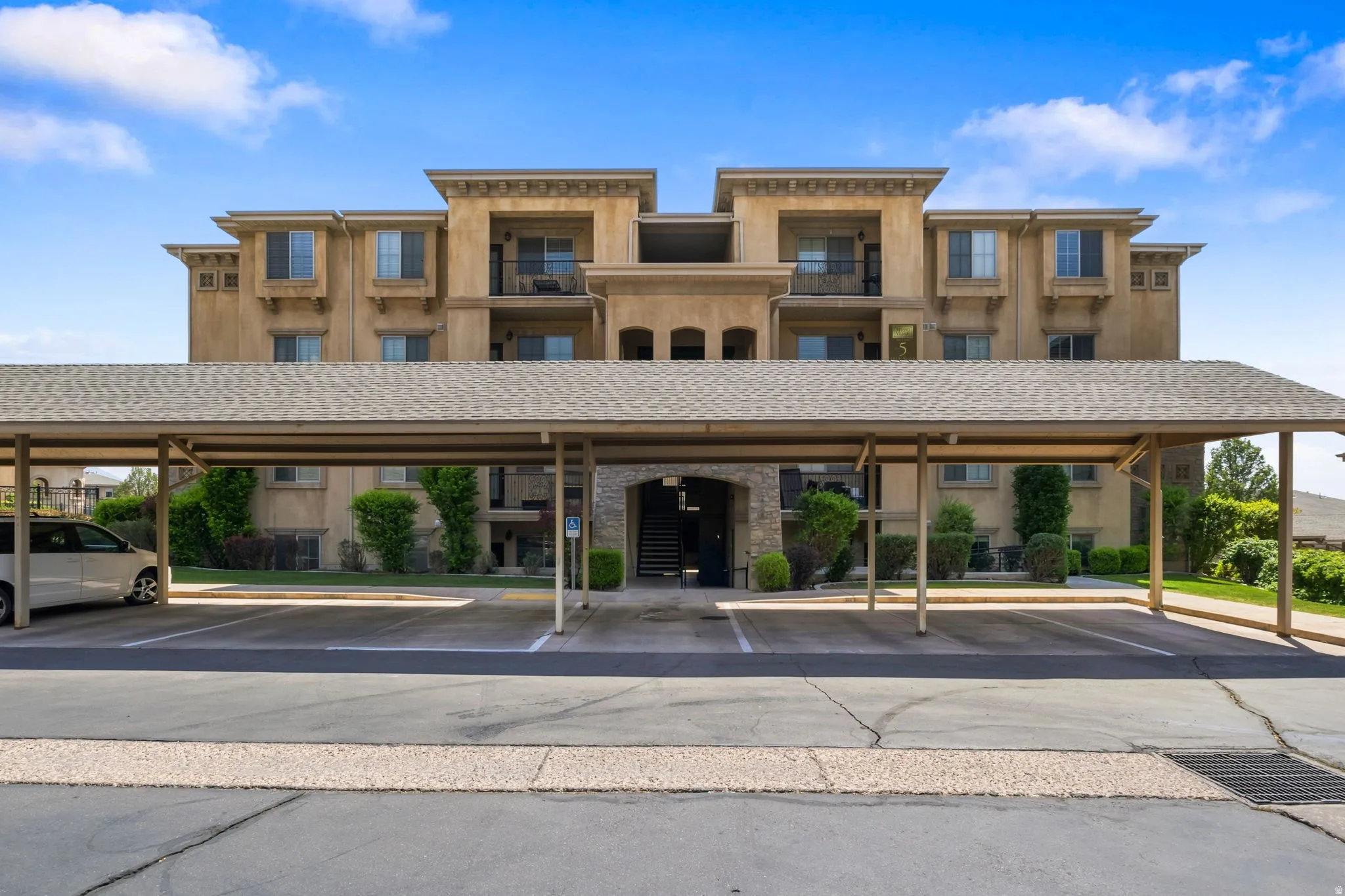 Elegant multi-story residential building featuring warm-toned brick exterior with symmetrical architectural detailing, multiple windows with individual units, and a covered ground-level portico with columns