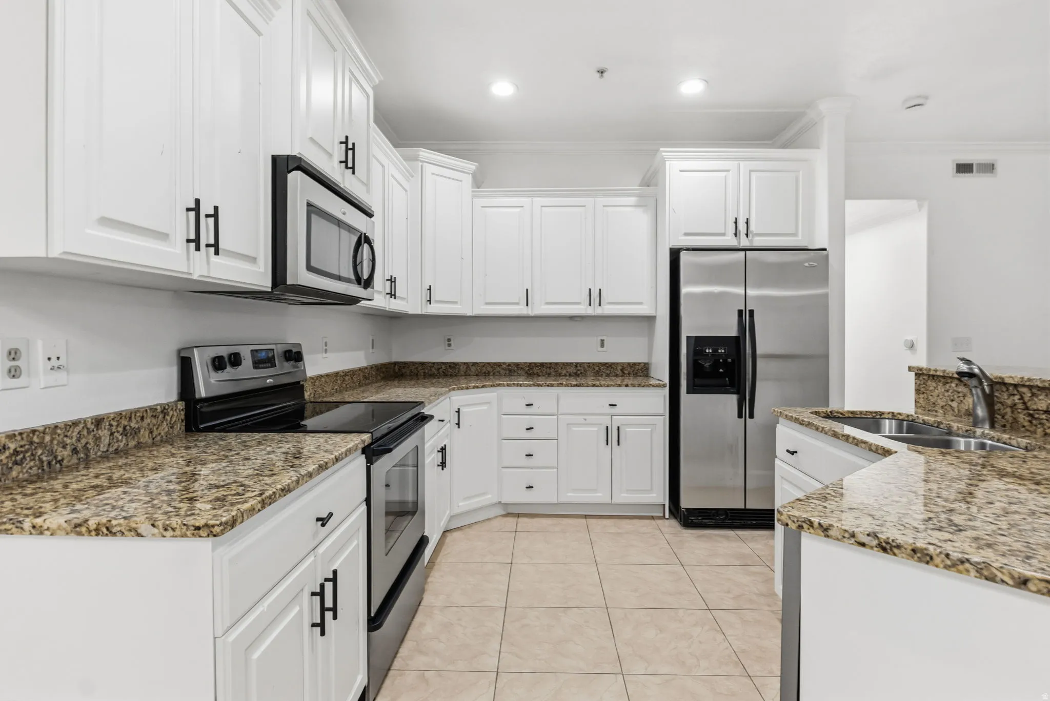 Kitchen featuring white cabinetry, granite countertops, stainless steel appliances, and tile flooring
