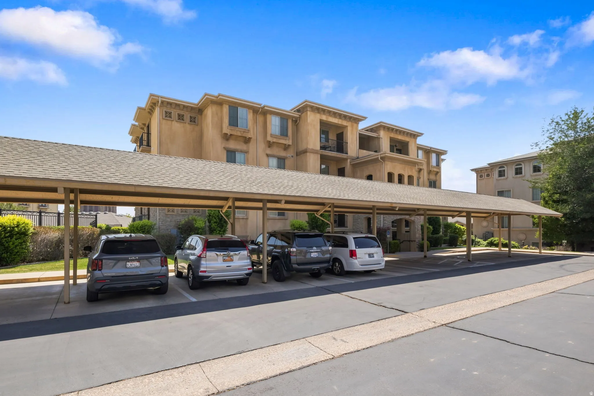Covered parking structure with multiple spaces, featuring a neutral-toned exterior building with balconies