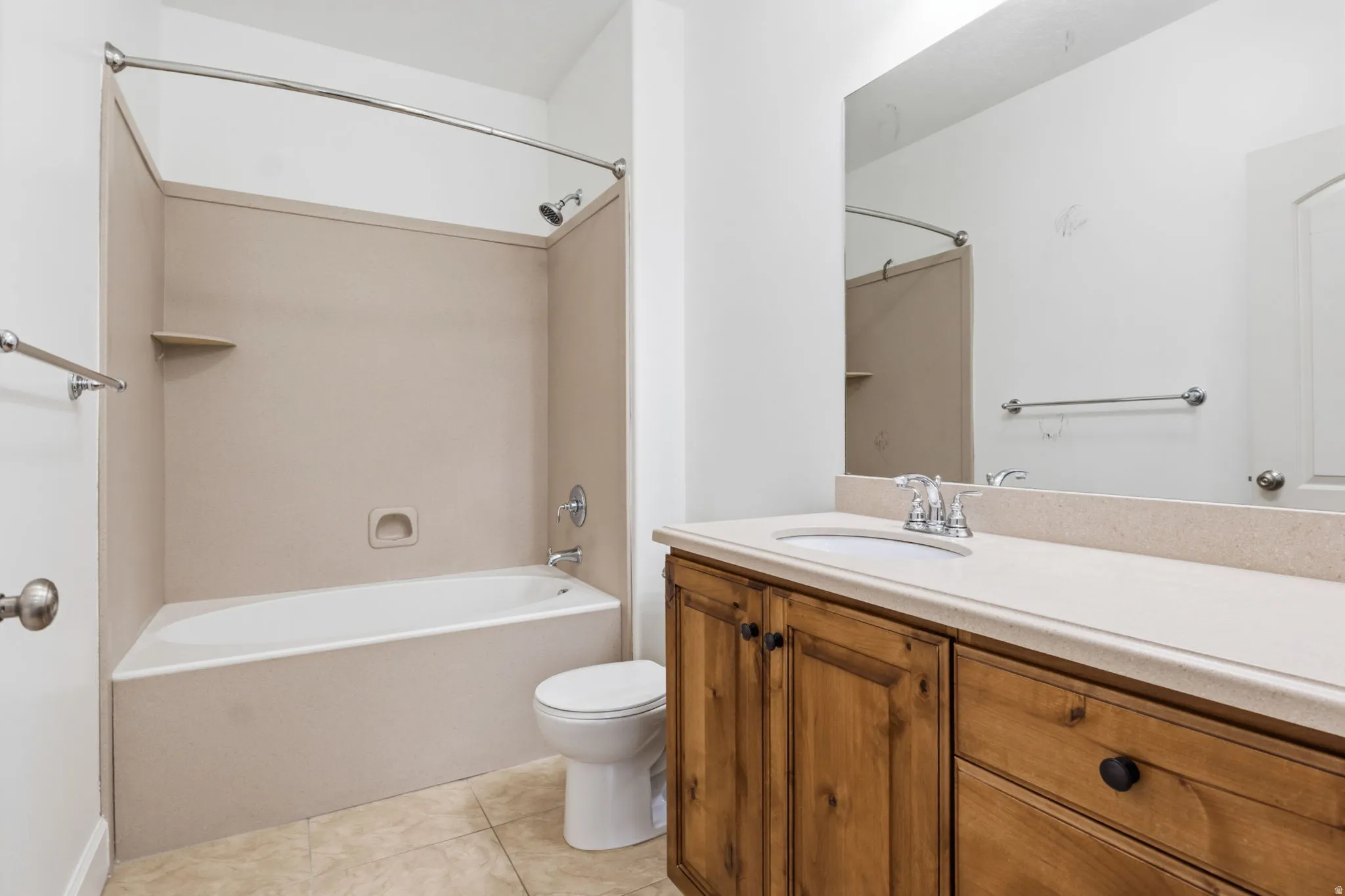 Bathroom featuring a full tub with shower, wood-finish vanity, light-toned countertop, and tile flooring