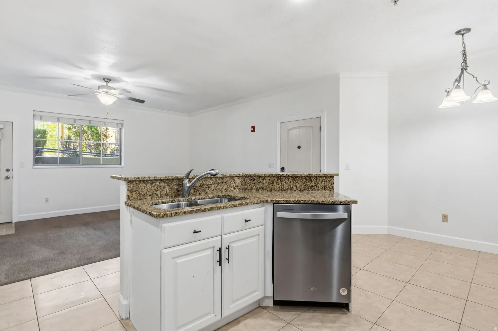 Kitchen island with a double basin sink, stainless steel dishwasher, and granite-look countertop
