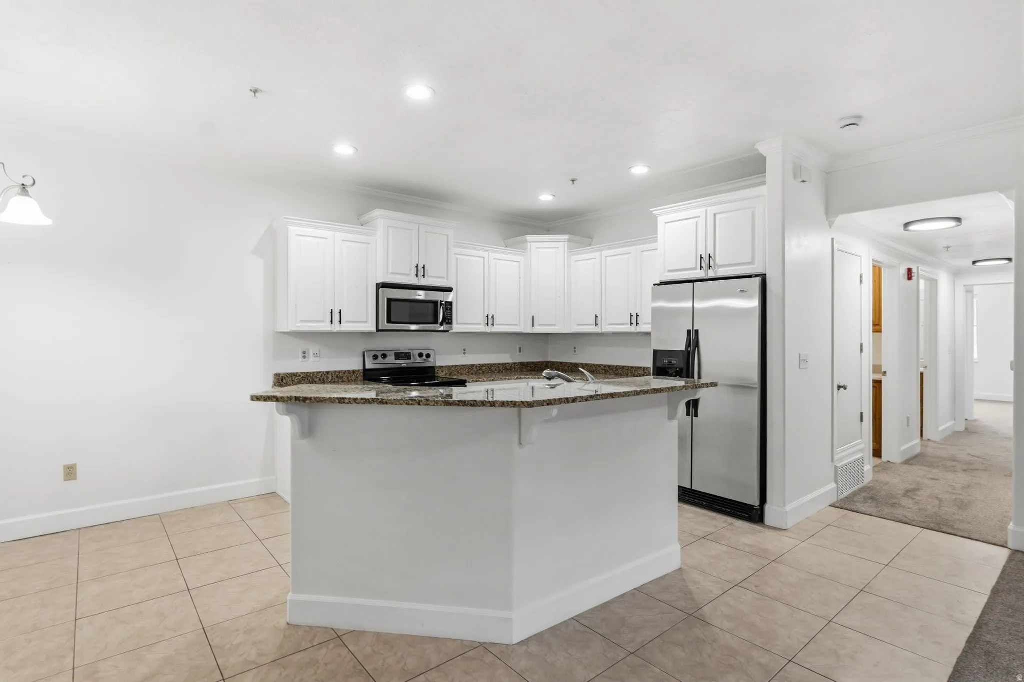 Kitchen featuring white cabinetry, stainless steel appliances, a multi-level island, recessed lighting, and tile flooring
