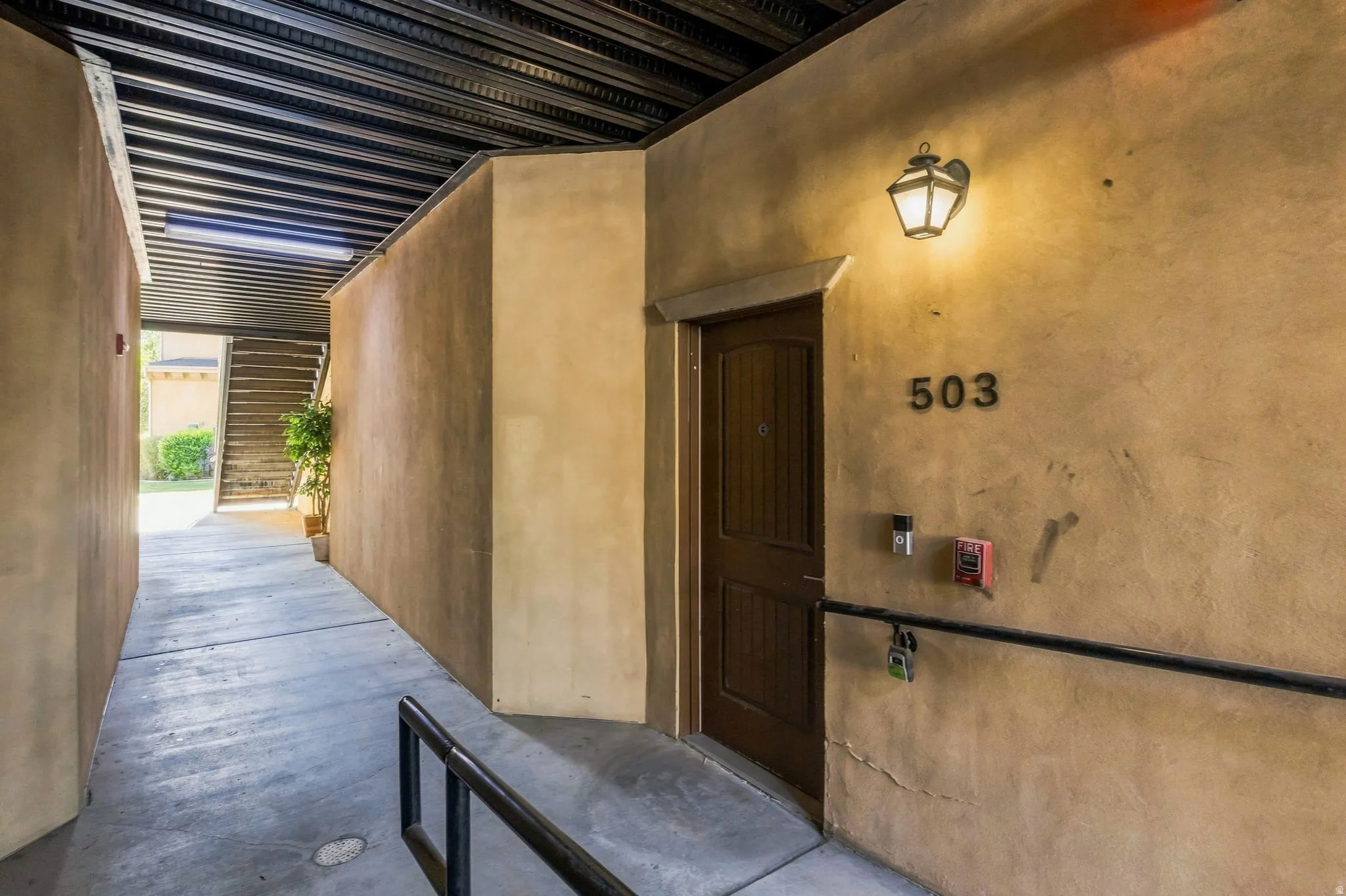 Entry door with panel detailing and a wall-mounted light fixture