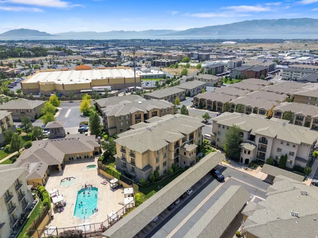 Outdoor swimming pool with integrated spa and surrounding paved sundeck, covered parking structures, and multi-story residential buildings with balconies