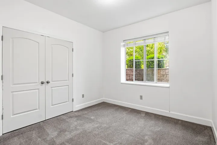 Neutral gray carpeting, white walls, and a window with blinds