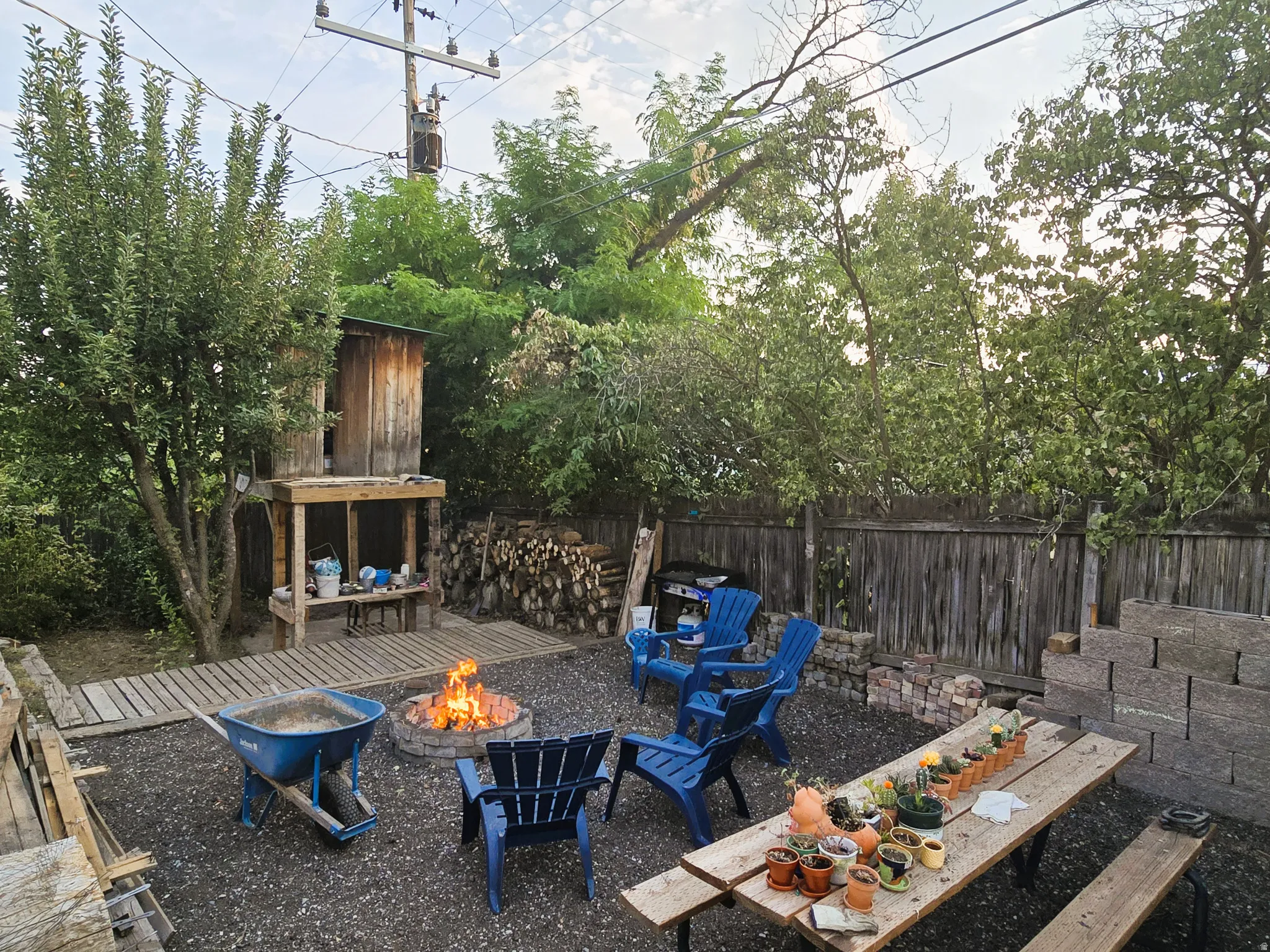 Expansive gravel patio featuring a built-in fire pit, privacy fencing, and mature trees