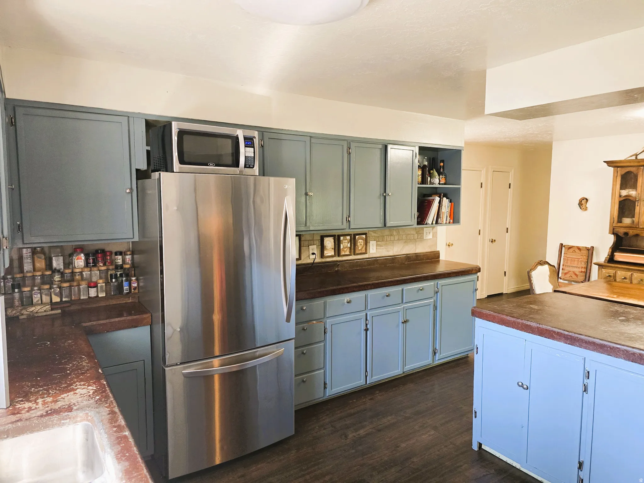 Kitchen featuring light blue cabinetry, dark wood-finish countertops, stainless steel appliances, and wood-finish flooring