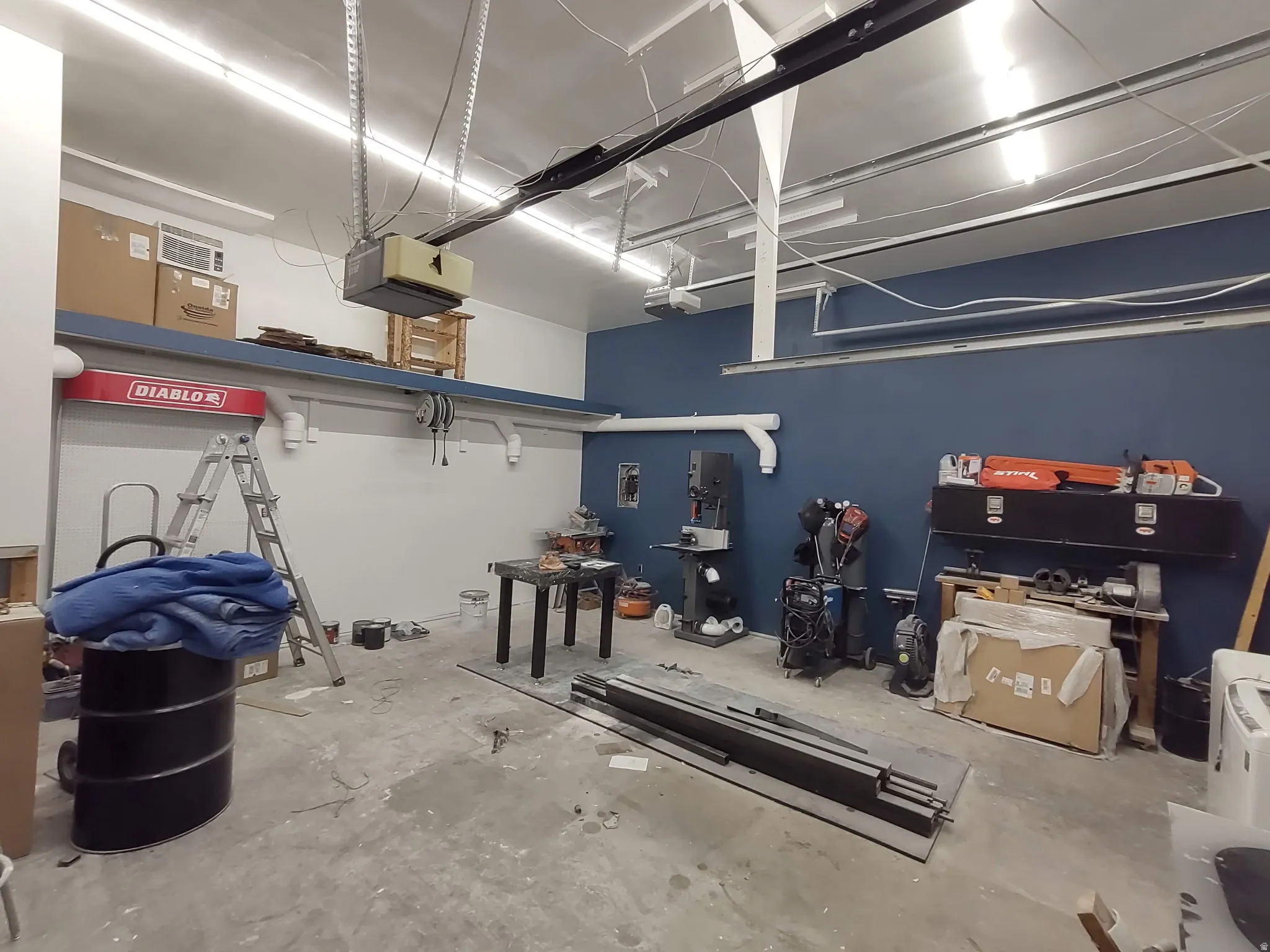 High ceilings, concrete flooring, track lighting, exposed structural elements, and a blue accent wall