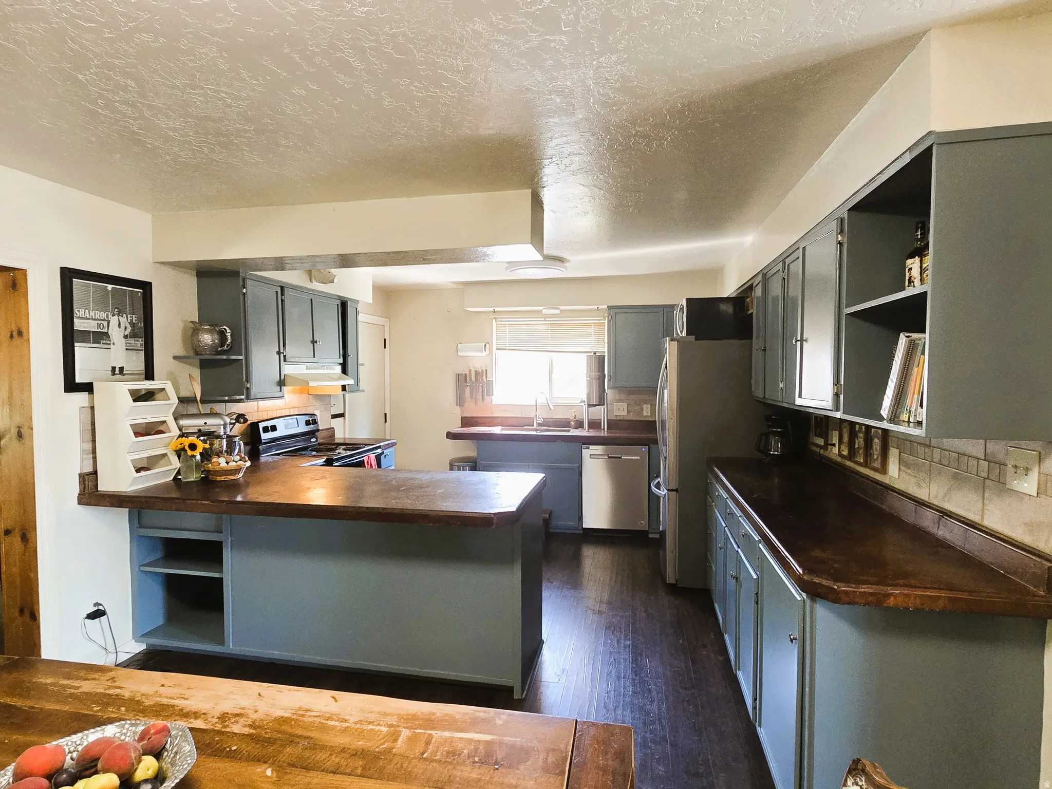 Kitchen featuring wood-finish flooring, blue cabinetry, dark countertops, and stainless steel appliances