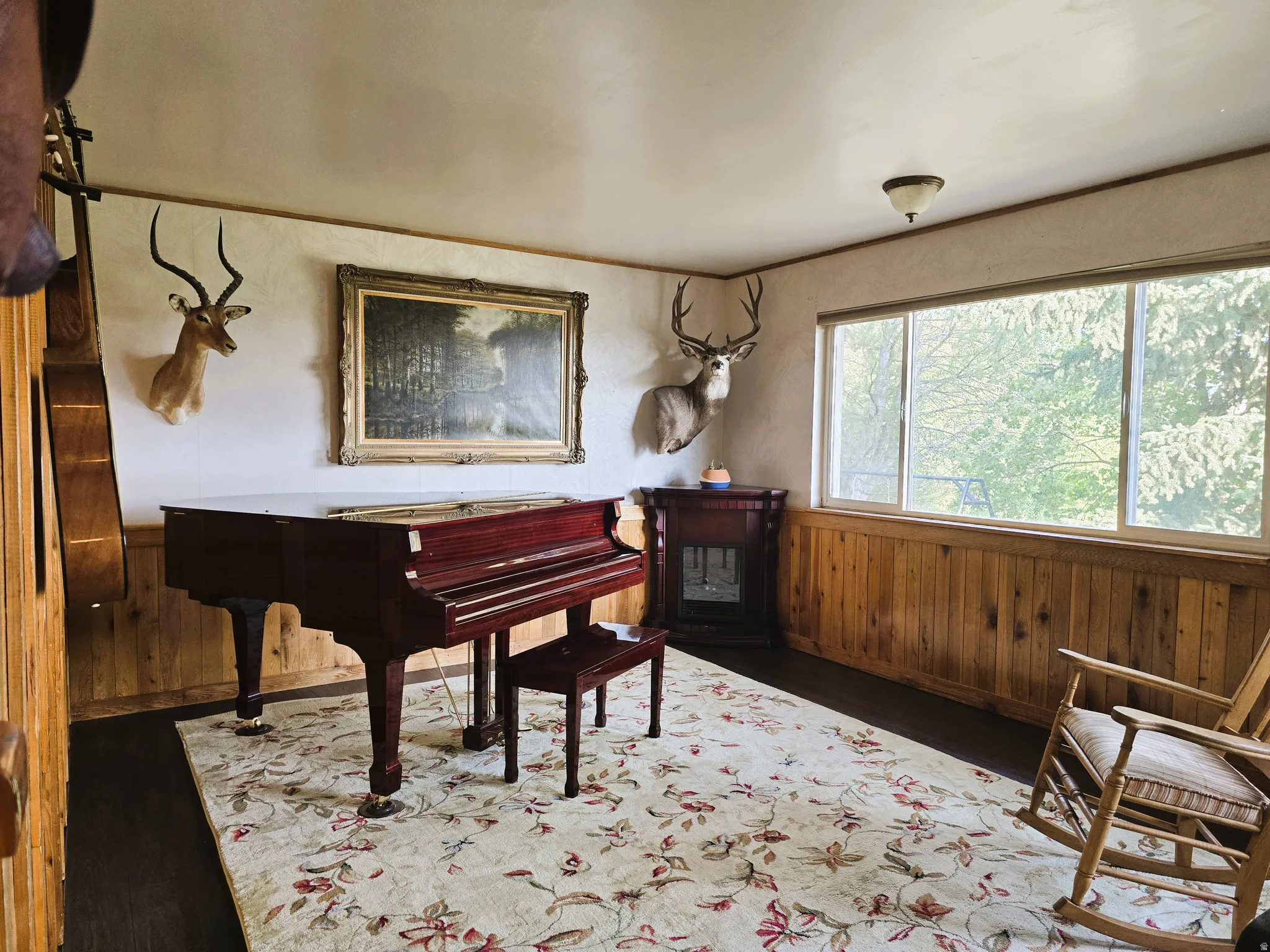 Hardwood flooring with wood paneling, large windows, and a built-in corner fireplace
