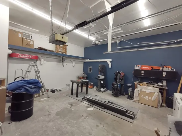 High ceilings, concrete flooring, track lighting, exposed structural elements, and a blue accent wall