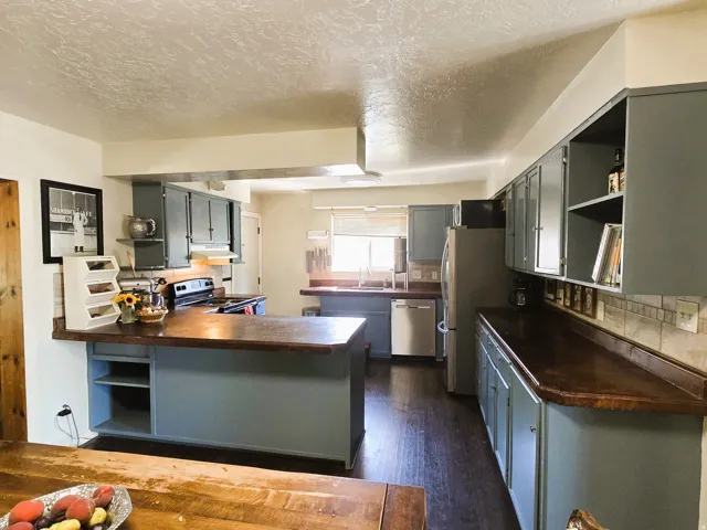 Kitchen featuring wood-finish flooring, blue cabinetry, dark countertops, and stainless steel appliances