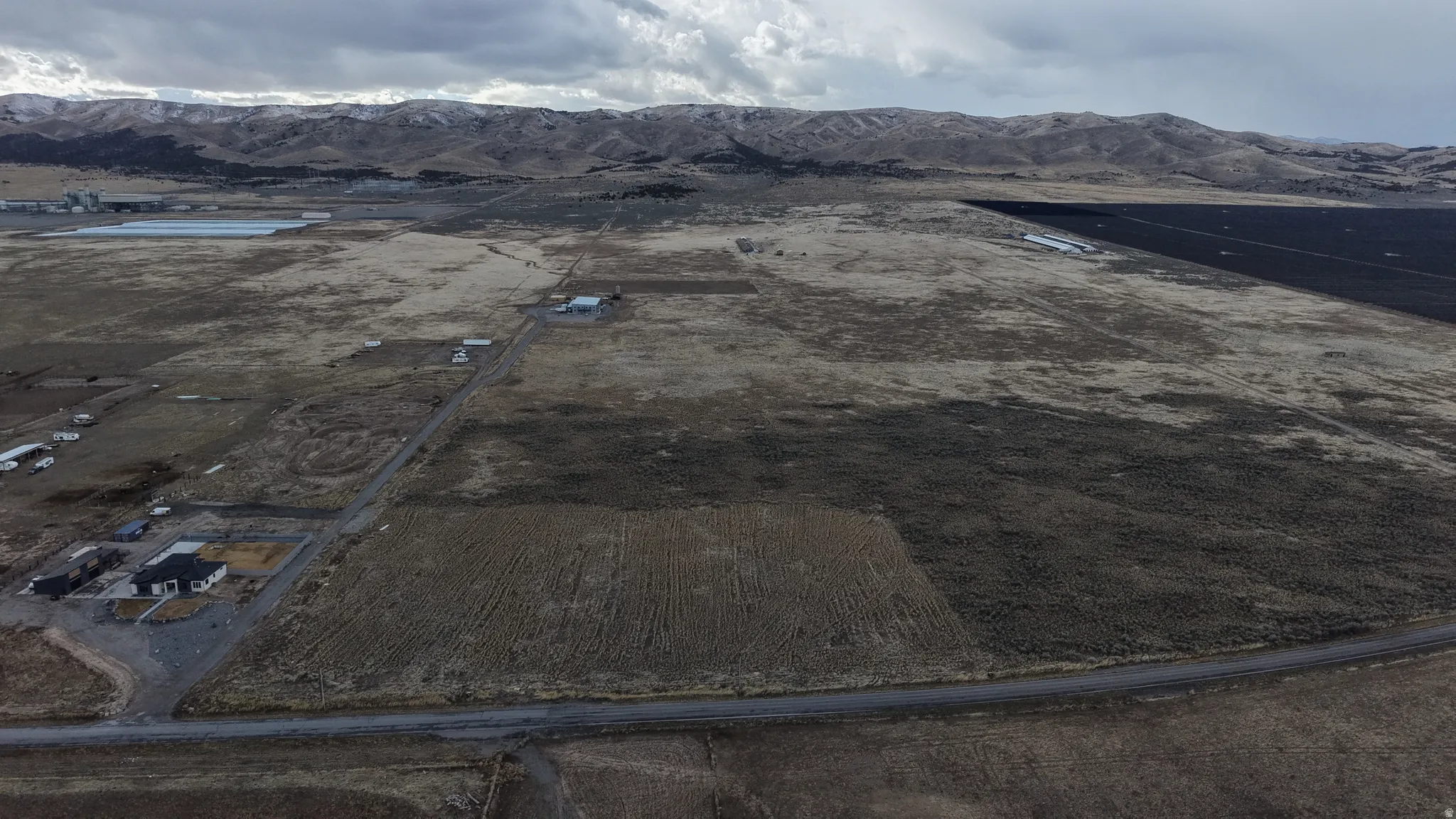Expansive undeveloped land featuring a paved road frontage, with mountain range backdrop