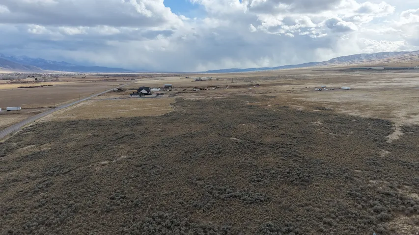 Expansive land parcel featuring natural shrubbery and distant mountain formations