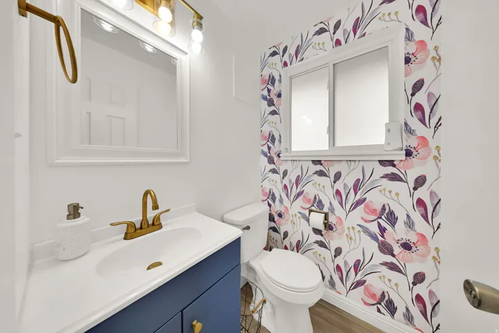 Built-in vanity with a white countertop and basin sink, brass-finish faucet, and coordinating mirror and light fixture