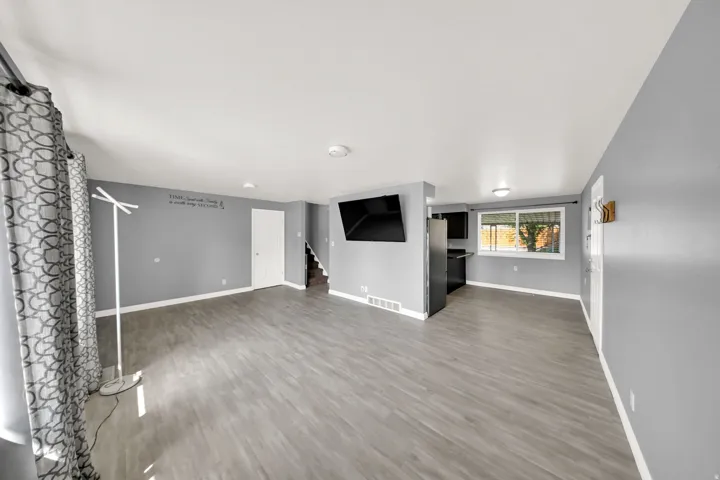 Open-concept living area with light gray walls, wood-finish flooring, and recessed lighting