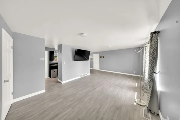 Spacious interior featuring light gray wall tones, wood-finish flooring, and white trim