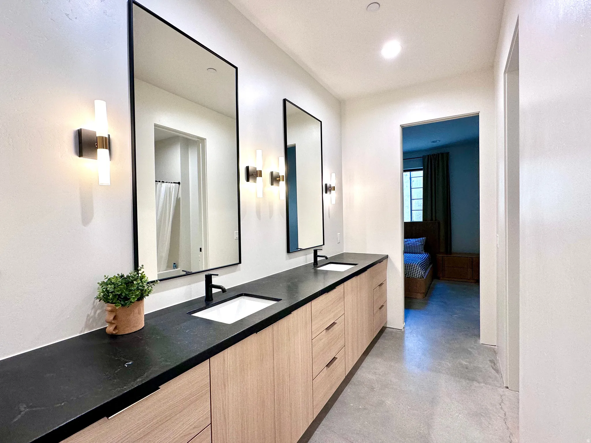 Double vanity featuring black countertops and wood-finish cabinetry