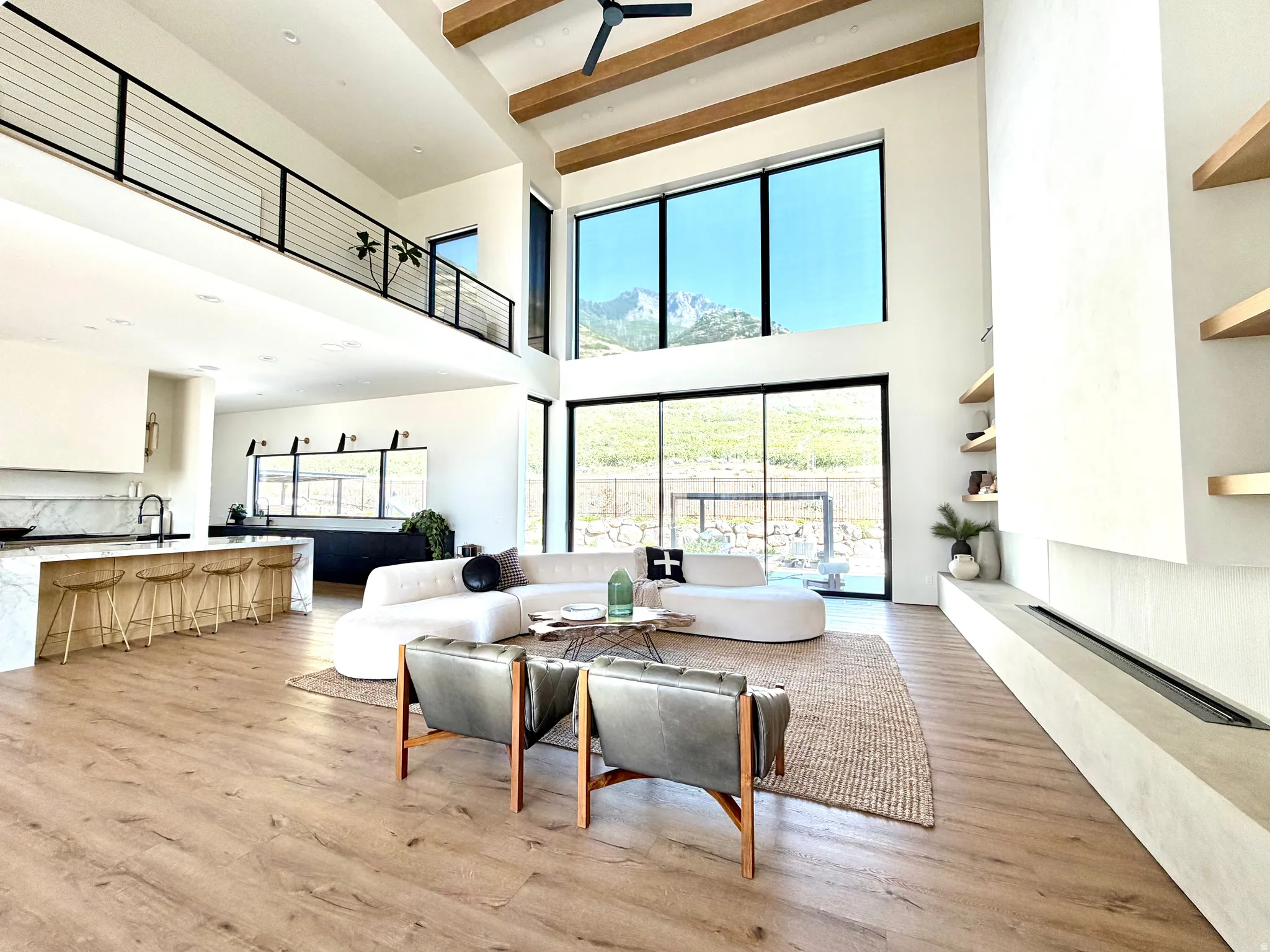 Open-concept living area with soaring ceilings, exposed wood beams, and expansive windows