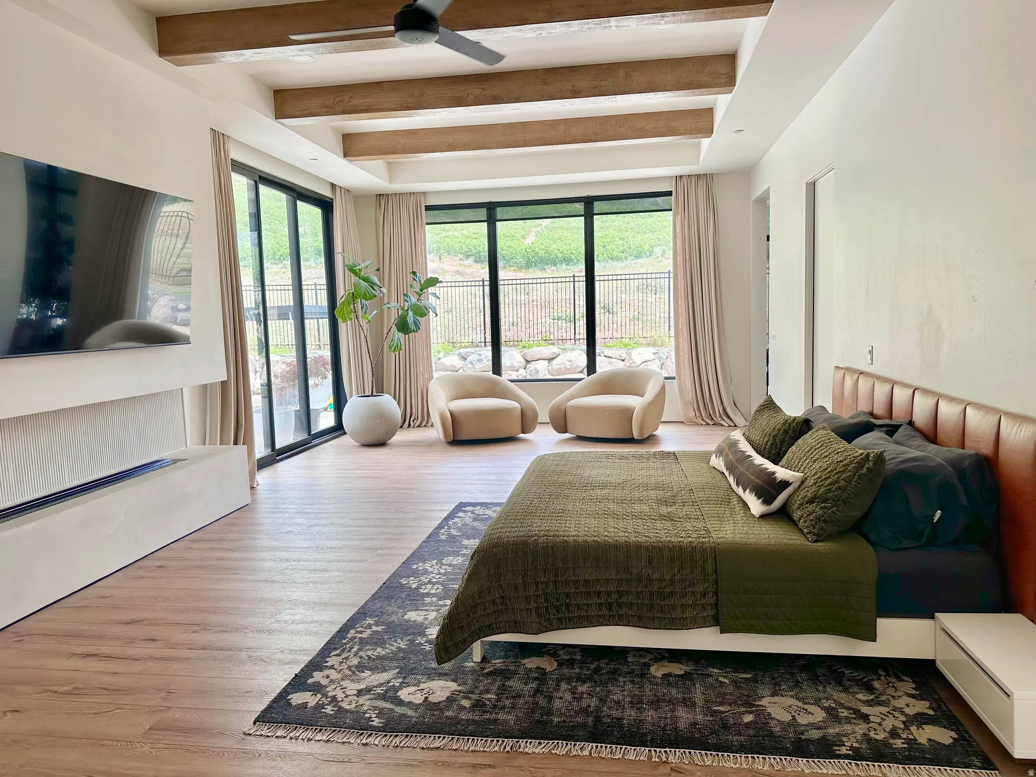 Wood-finish flooring with exposed ceiling beams and a modern ceiling fan