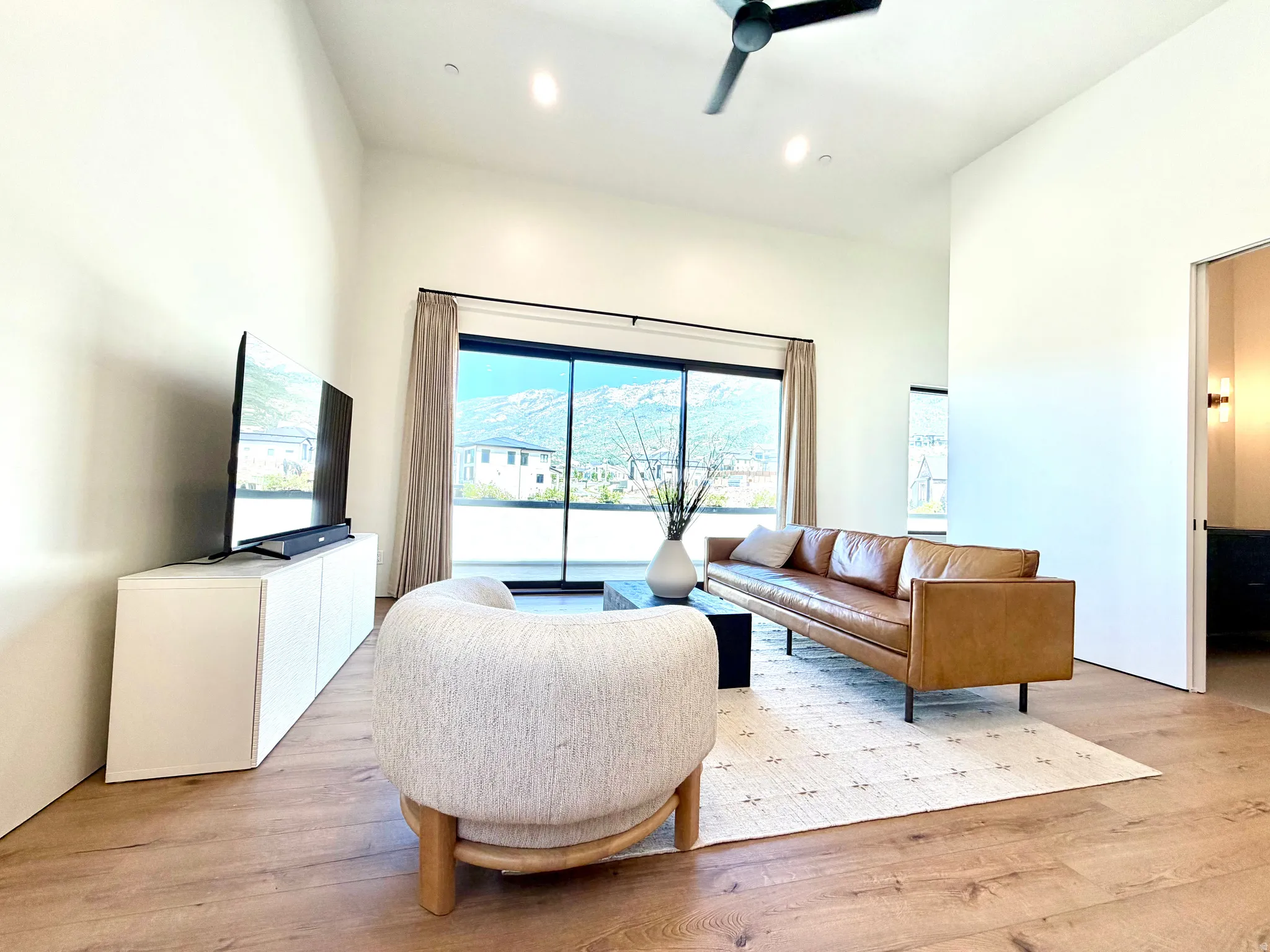 Vaulted ceilings with recessed lighting, wood-finish flooring, and a contemporary ceiling fan