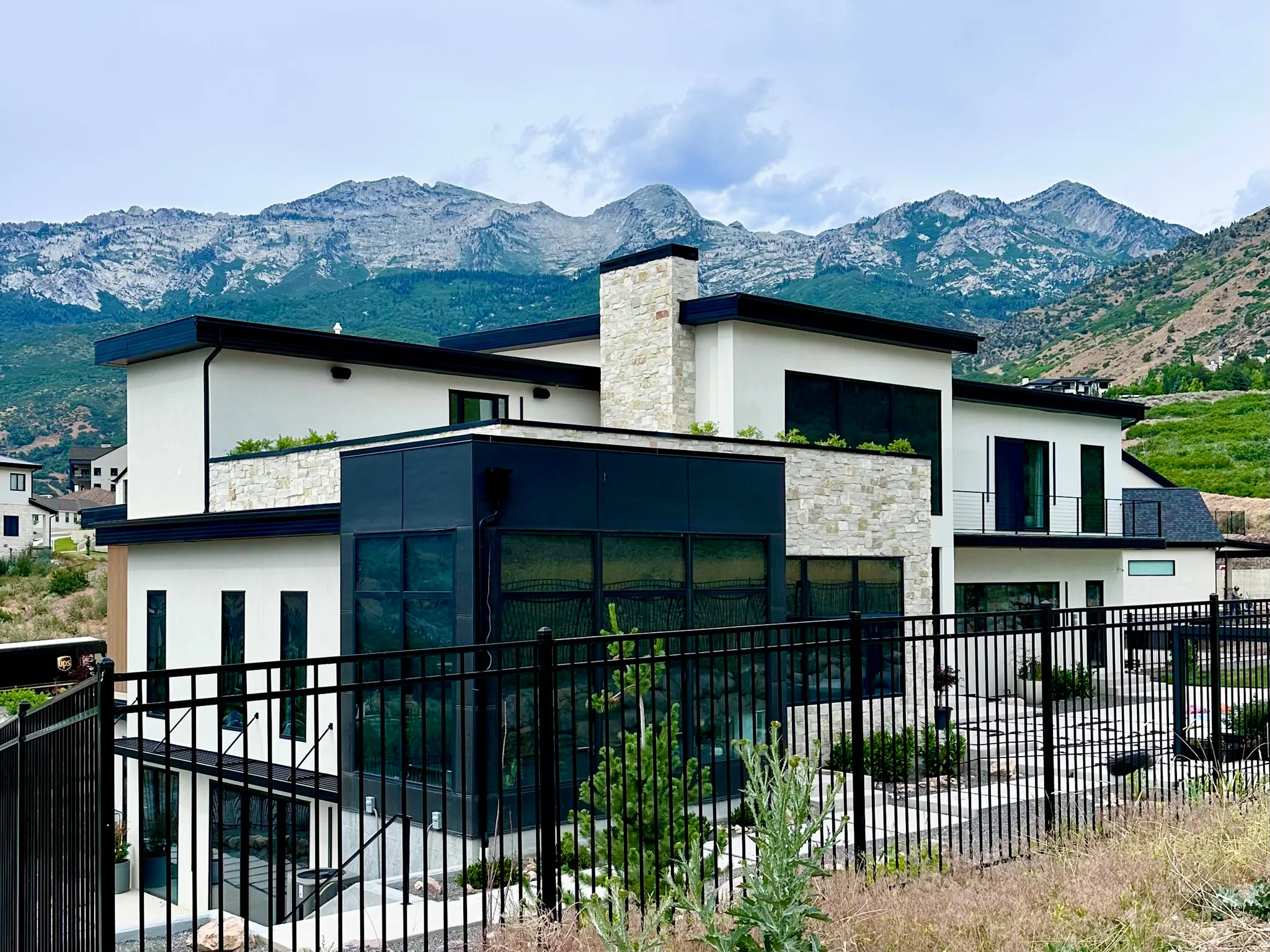 Contemporary architecture featuring a combination of stucco and stone veneer, dark trim, and multiple balconies