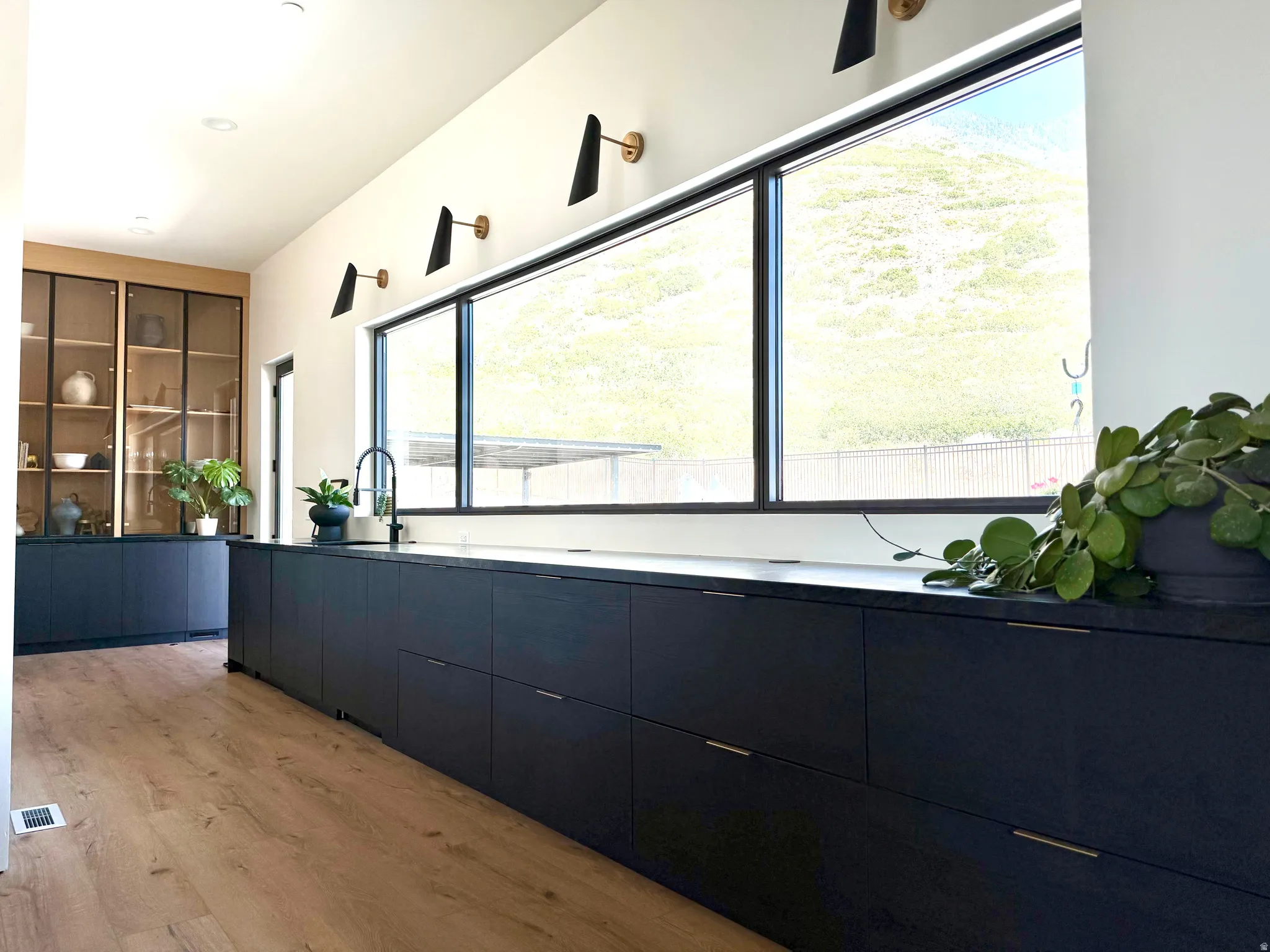 Expansive dark wood-finish cabinetry, wide plank wood-finish flooring, and large horizontal windows