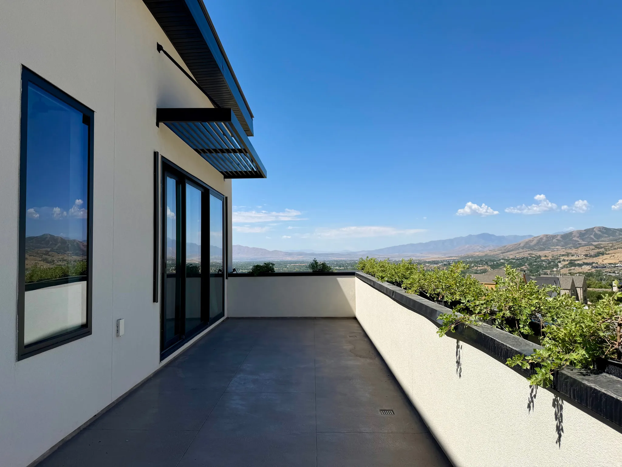 Exterior balcony featuring a smooth stucco finish, black-framed windows, and sliding glass doors