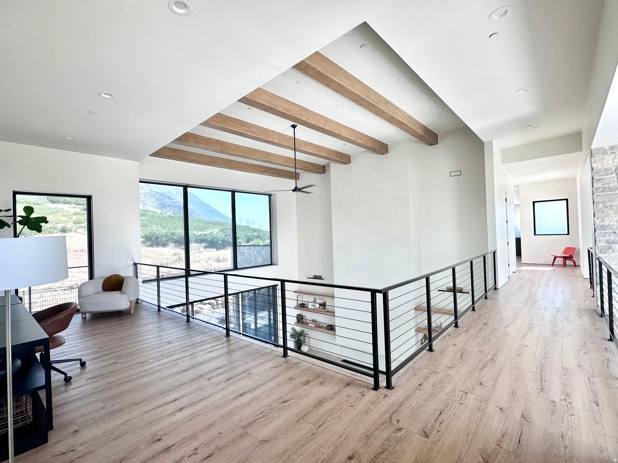 Open-concept loft with wood-finish flooring, a contemporary cable railing system, and recessed lighting