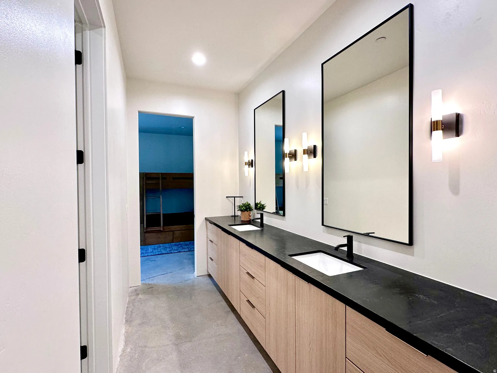 Double vanity with wood-finish cabinetry, black countertop, and integrated sinks