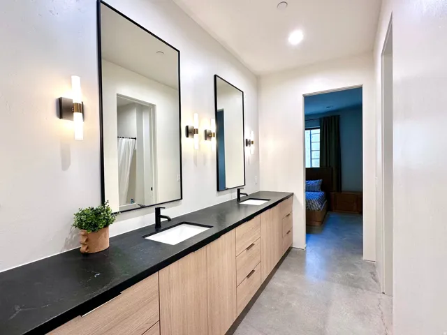 Double vanity featuring black countertops and wood-finish cabinetry