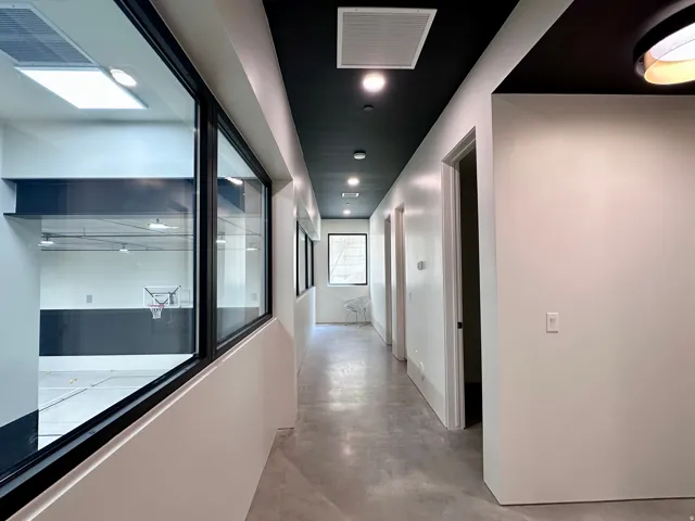 Expansive hallway with concrete flooring, recessed lighting, and a dark ceiling