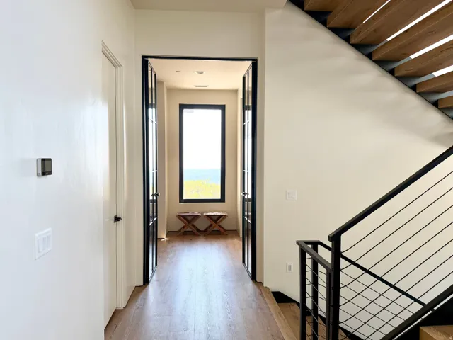 Engineered wood-finish flooring, metal-framed double doors, contemporary window, open-tread staircase with black metal railing