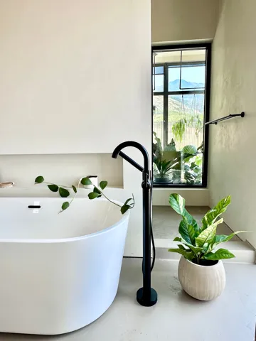 Freestanding soaking tub with a floor-mounted matte black faucet