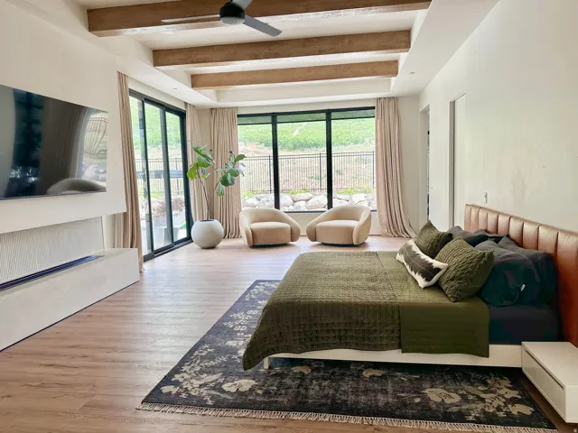 Wood-finish flooring with exposed ceiling beams and a modern ceiling fan