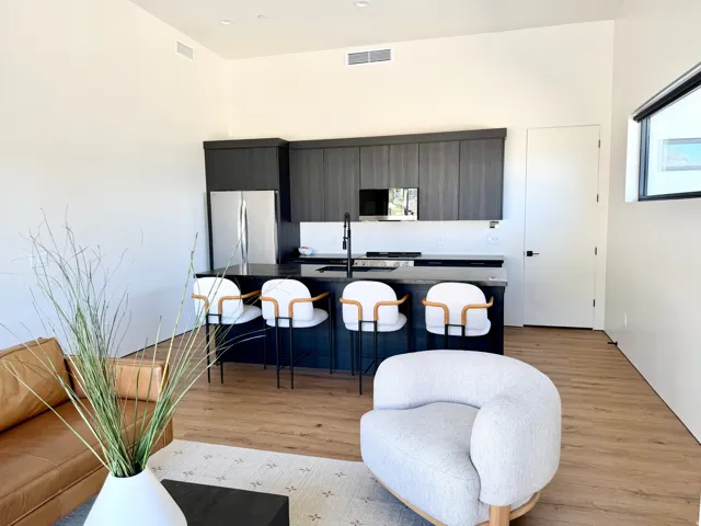 Open-concept kitchen featuring dark wood-finish cabinetry, stainless steel appliances, a kitchen island with seating, and wood-finish flooring throughout