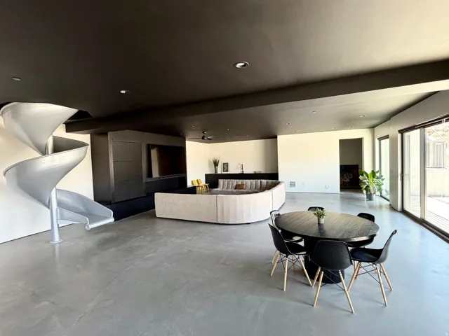 Spacious open-concept room featuring concrete flooring, a spiral slide, and sliding glass doors