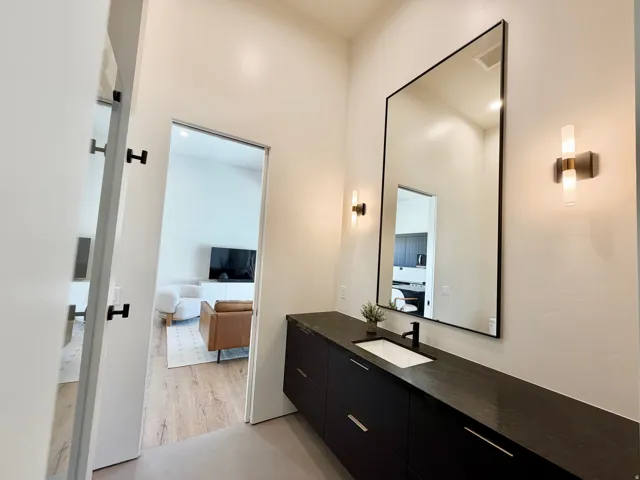 Floating vanity with a built-in rectangular sink, matte black faucet, and dark countertop