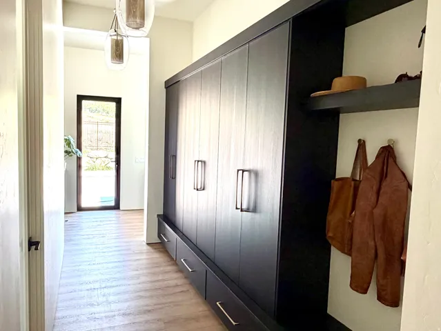 Built-in dark wood cabinetry, wood-finish flooring, recessed lighting, and modern pendant lighting fixtures