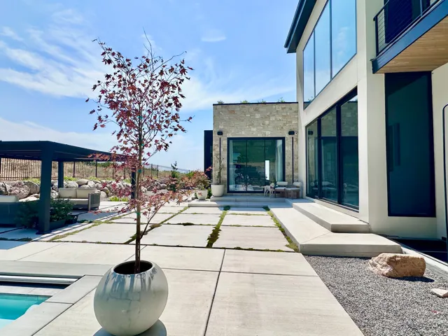 Modern exterior featuring expansive glass walls, stone facade, and a covered patio area