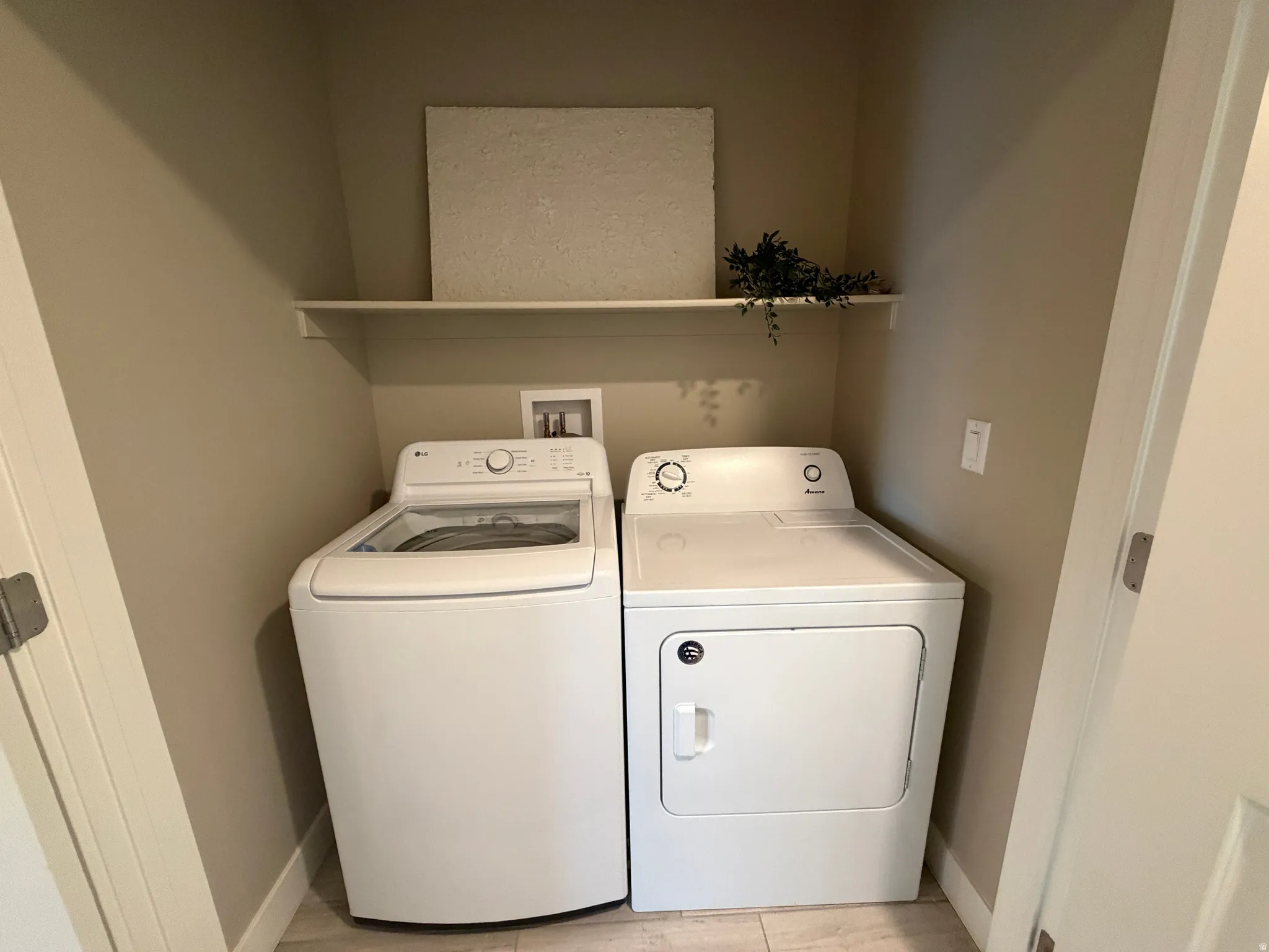 Built-in laundry area featuring a white shelf and light-toned wall paint